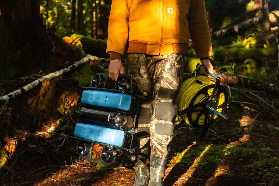 Carrying a BlueROV2 and tether spool through the forest